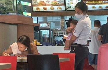 Gerente do McDonald’s segura bebê enquanto a mãe preenche o formulário de emprego